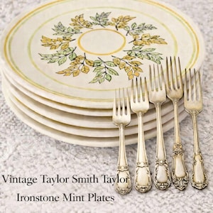 Może przedstawiać: Stos talerzy Ironstone Mint w stylu vintage z motywem liści w kolorze żółtym, zielonym i brązowym. Pięć niedopasowanych srebrnych widelców do sałatek ułożonych przed talerzami. Tekst na zdjęciu brzmi "Vintage Taylor Smith Taylor Ironstone Mint Plates with five mismatched salad forks."