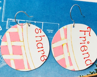 May include: A pair of round earrings with a pink and white checkered pattern. One earring says "Friend" and the other says "Share" in red lettering.