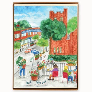 May include: Watercolor painting of a street scene with a red brick building and a sign that says "Welcome to Green." People are walking, biking, and sitting at tables. A person carries a potted plant. The artwork is framed in a brown border.