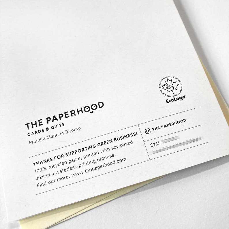 May include: The Paperhood card and gift company logo with the text "The Paperhood Cards & Gifts Proudly Made in Toronto" and the text "Thanks for supporting green business! 100% recycled paper, printed with soy-based inks in a waterless printing process. Find out more: www.thepaperhood.com". The logo also includes the EcoLogo certification mark.