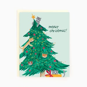 May include: A Christmas card with a green Christmas tree decorated with red ornaments and lights. Five cats are climbing the tree, and one cat is sitting in a yellow box with a red bow. The text "meowy christmas!" is written in black on the card.