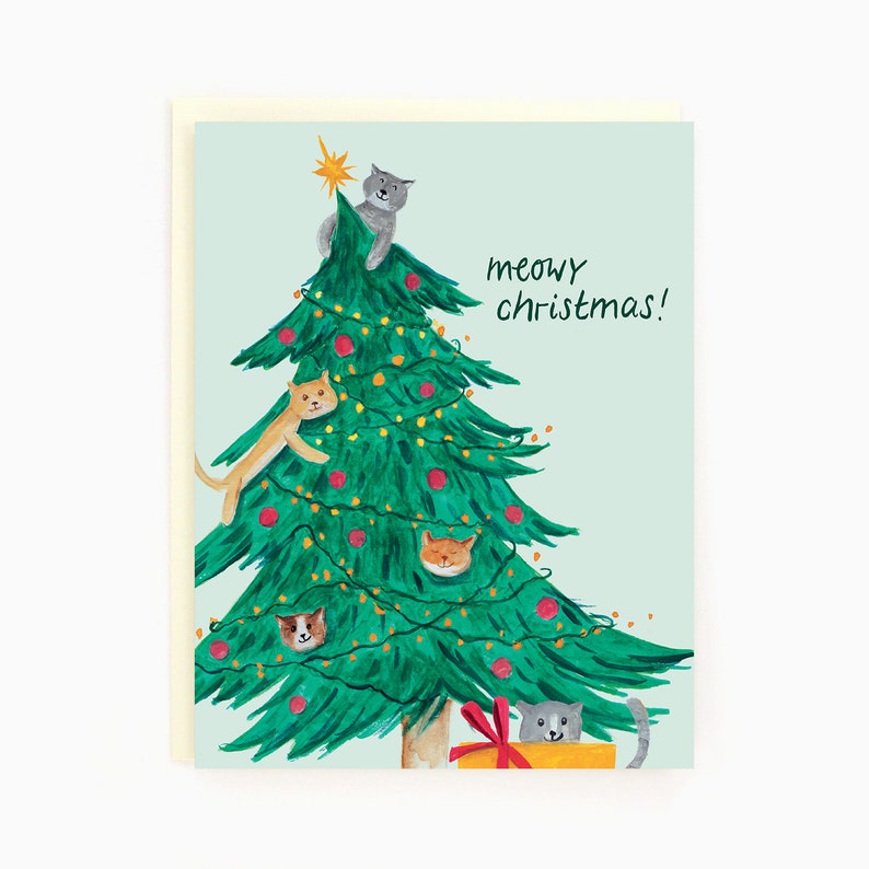 May include: A Christmas card with a green Christmas tree decorated with red ornaments and lights. Five cats are climbing the tree, and one cat is sitting in a yellow box with a red bow. The text "meowy christmas!" is written in black on the card.