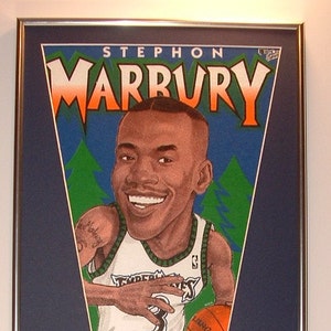 May include: A framed pennant featuring a cartoon illustration of Stephon Marbury, a basketball player for the Minnesota Timberwolves. The pennant is blue with green and white accents. The pennant also features a basketball with the number 3 on it. The frame is silver and includes several smaller photos of Marbury playing basketball.