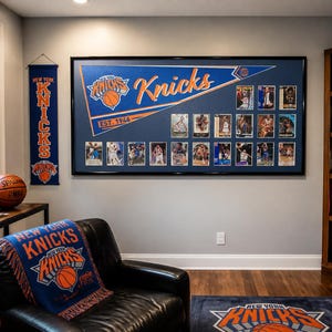 May include: A large framed display featuring a blue New York Knicks pennant with the text 'EST. 1946' and numerous basketball trading cards. The room includes a Knicks throw blanket on a black chair, a vertical banner, and a basketball on a side table.