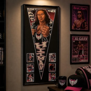 May include: A room featuring wrestling memorabilia. A large framed poster of Bret Hart is the focal point, along with framed posters, championship belts, and a neon heart-shaped sign. A shelf displays belts, DVDs, and a figurine.