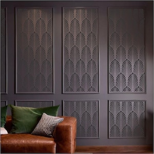 May include: A dark gray wall with a geometric pattern stencil design. The stencil is in the shape of overlapping fan-like shapes. The wall is divided into nine sections, each with the same pattern. A brown leather couch with green and white pillows sits in front of the wall.