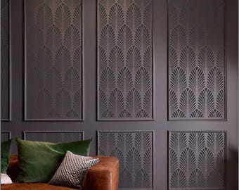 May include: A dark gray wall with a geometric pattern stencil design. The stencil is in the shape of overlapping fan-like shapes. The wall is divided into nine sections, each with the same pattern. A brown leather couch with green and white pillows sits in front of the wall.