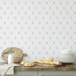 May include: A white kitchen countertop with a light brown wooden cutting board, a white mug, a green plant, two loaves of bread, and two baguettes on a wooden cutting board. The wall behind the countertop has a white and light brown repeating pattern of bees.