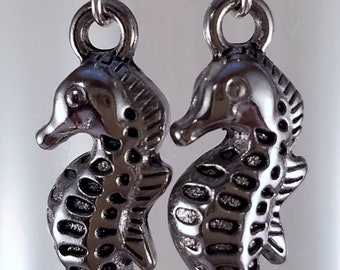 May include: A pair of silver earrings featuring a detailed seahorse design. The earrings are made of metal and have a silver finish.
