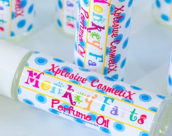 May include: A white roll-on bottle with a blue and white polka dot label. The label says "Xplosive Cosmetix Monkey Farts Perfume Oil" and includes the website address "www.XplosiveCosmetix.com".