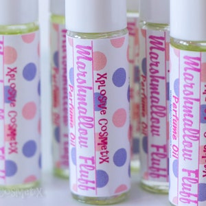 May include: Several glass roll-on perfume bottles with white caps. Each bottle has a label with the text "Marshmallow Fluff Perfume Oil" and "Xplosive Cosmetix" in pink and purple polka dots.