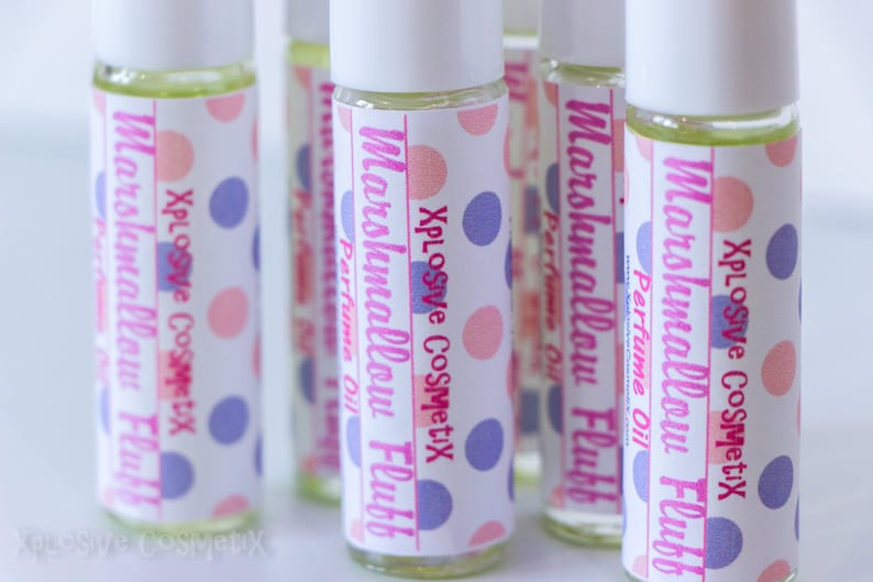 May include: Several glass roll-on perfume bottles with white caps. Each bottle has a label with the text "Marshmallow Fluff Perfume Oil" and "Xplosive Cosmetix" in pink and purple polka dots.