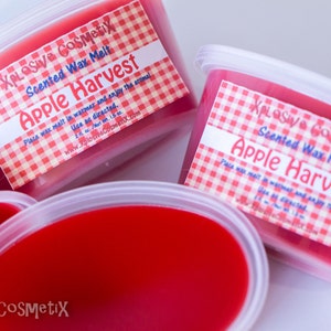 May include: Three containers of red scented wax melt with a white label that says "XPLOSIVE COSMEtix Scented Wax Melt Apple Harvest". The label has a red and white checkered pattern.