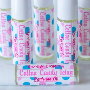 K&ouml;nnte beinhalten: Eine Sammlung von Roll-on-Parf&uuml;m&ouml;len mit der Aufschrift "Cotton Candy Icing" und rosa und blauen Tupfen. Die Flaschen sind klar, und die Etiketten enthalten den Markennamen "Xplosive Cosmetix" und die Website-Adresse.