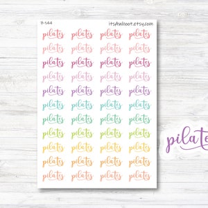 May include: A sheet of colorful stickers with the word "pilates" written in cursive. The stickers are arranged in rows of four, with each row featuring a different color. The colors are pink, purple, teal, green, yellow, and orange. The sheet is on a white wooden background.