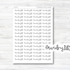 May include: A sheet of stickers with the text "laundry DAY" repeated multiple times in a handwritten font. The stickers are on a white wood background.