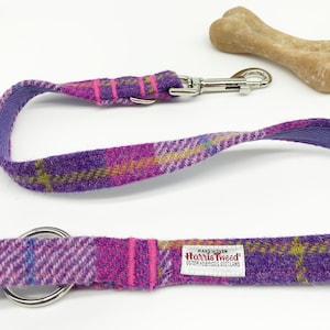 Puede incluir: Correa para perro de cuadros morados, rosas y verdes con un clip y un anillo plateados. La correa está hecha de Harris Tweed, una tela tejida a mano en las Hébridas Exteriores de Escocia.