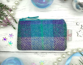 May include: A small blue, green, and purple plaid zippered pouch with a white label that says "Harris Tweed."