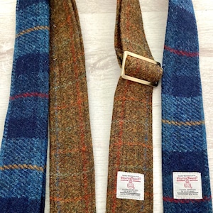 May include: Two neckties made of tweed fabric. One is blue with red and yellow stripes, the other is brown with orange and green stripes. Both have a label that says "Harris Tweed" and "Outer Hebrides of Scotland".