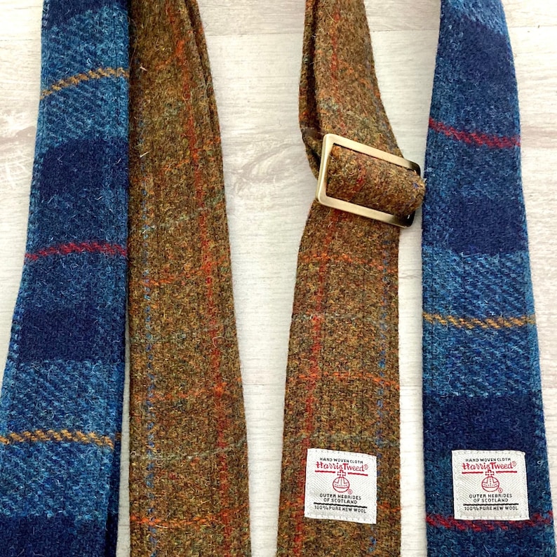 May include: Two neckties made of tweed fabric. One is blue with red and yellow stripes, the other is brown with orange and green stripes. Both have a label that says "Harris Tweed" and "Outer Hebrides of Scotland".
