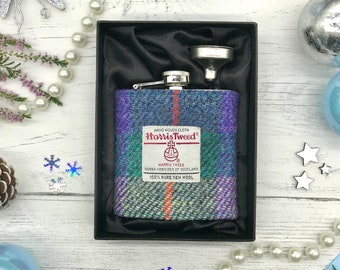 May include: A stainless steel hip flask with a funnel, covered in a purple, green, and blue plaid Harris Tweed fabric. The flask is in a black velvet box.