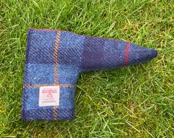 May include: A blue, black, and orange plaid putter cover made of Harris Tweed fabric. The cover features a rectangular white label with the red Harris Tweed logo and text that reads Hand Woven Cloth, Harris Tweed, Outer Hebrides of Scotland, 100% Pure New Wool.