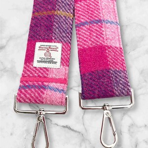 Puede incluir: Correa de Harris Tweed a cuadros rosa y morado con cierres plateados. La correa est&aacute; hecha de 100% lana virgen pura y est&aacute; tejida a mano. La etiqueta dice "Tela tejida a mano Harris Tweed&reg; Outer Hebrides of Scotland 100% Lana Virgen Pura".