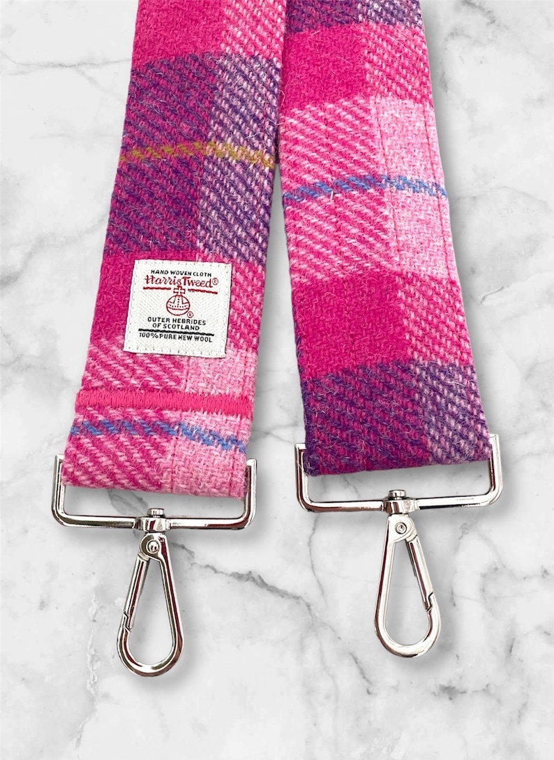 Puede incluir: Correa de Harris Tweed a cuadros rosa y morado con cierres plateados. La correa est&aacute; hecha de 100% lana virgen pura y est&aacute; tejida a mano. La etiqueta dice "Tela tejida a mano Harris Tweed&reg; Outer Hebrides of Scotland 100% Lana Virgen Pura".