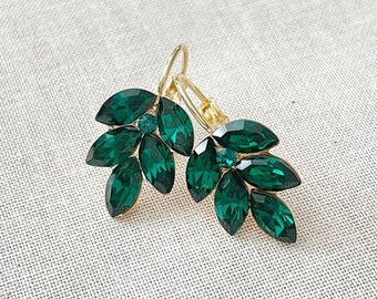 May include: A pair of gold earrings with a cluster of emerald green crystal leaves. The earrings have a hook closure.