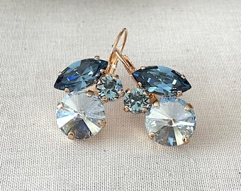 May include: Gold tone earrings with a cluster of blue and clear crystal rhinestones. The earrings have a teardrop shape and are perfect for adding a touch of sparkle to any outfit.