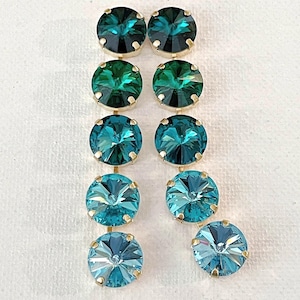May include: A pair of drop earrings featuring five round, faceted crystals in a vertical gradient, transitioning from dark forest green at the top to a light sky blue at the bottom, set in gold-toned metal prongs in a linear arrangement.