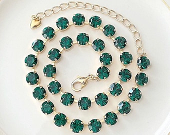 May include: A gold chain necklace with emerald green crystal beads. The necklace has a heart-shaped clasp.