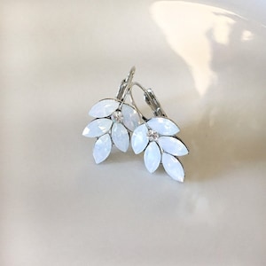 May include: A pair of silver hoop earrings with white opal-like stones in a floral design.