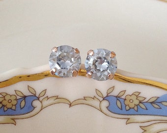 May include: A pair of rose gold stud earrings with clear round cubic zirconia stones.