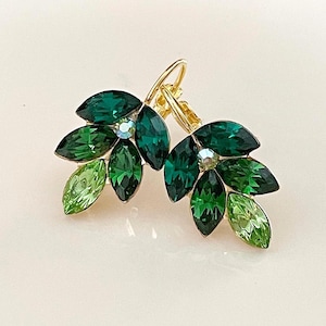 May include: A pair of gold tone clip-on earrings with a cluster of green and light green marquise-shaped rhinestones.