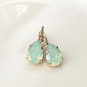 May include: A pair of gold teardrop earrings with light blue opal stones.