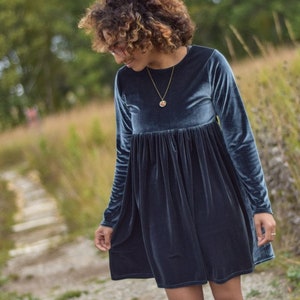 May include: A blue velvet dress with long sleeves and a round neckline.