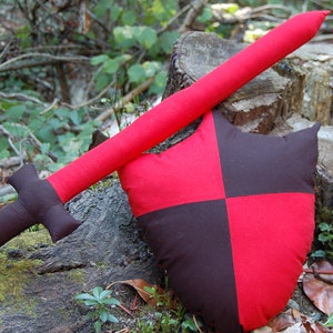 May include: A red and black fabric sword and shield set. The sword is made of fabric and has a red handle. The shield is also made of fabric and has a red and black checkered pattern.