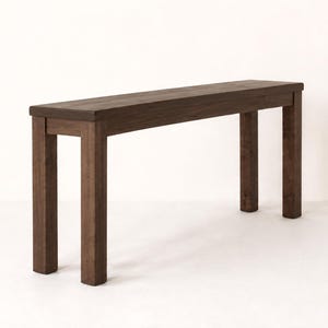 May include: A rectangular wooden console table with a dark brown finish. The piece features a flat, elongated top surface supported by four sturdy, straight legs positioned at each corner, creating a simple and functional furniture design.
