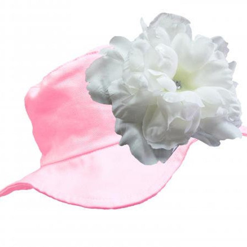 May include: A pink satin sun hat with a large white flower on top.