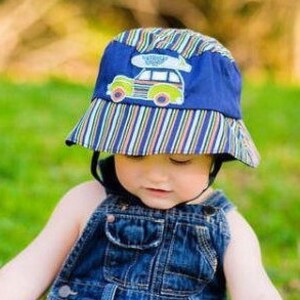 May include: A blue and green striped bucket hat with a car and surfboard applique. The hat has a chin strap.