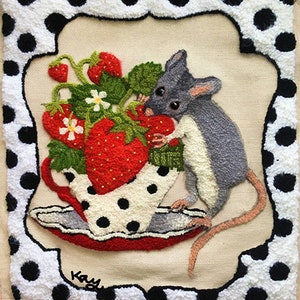May include: A gray mouse peeking out of a white teacup with black polka dots, filled with red strawberries. The teacup is on a red saucer with black polka dots. The background is a white and black polka dot fabric.