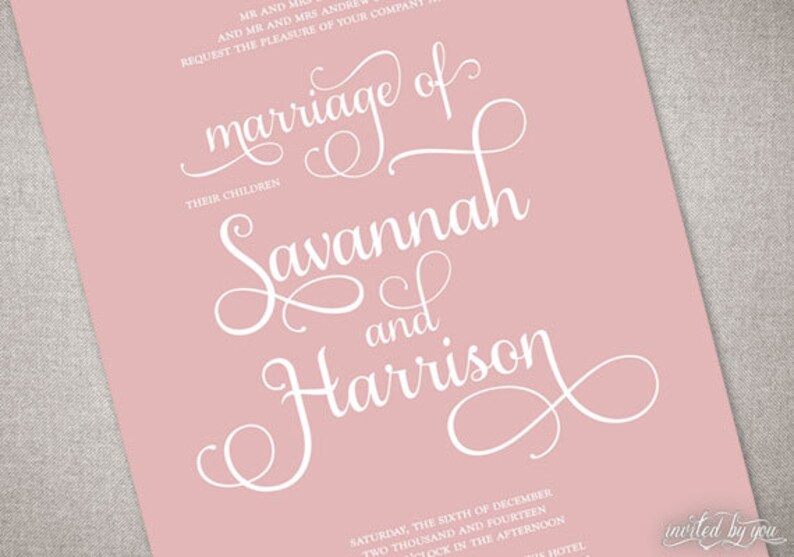May include: A pink wedding invitation with elegant white script. The text reads "marriage of Savannah and Harrison." Additional text includes the date and time of the ceremony. The invitation is angled, showing a corner of a gray textured surface.