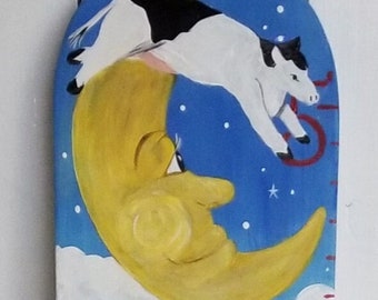 May include: A wooden growth chart painted with a whimsical scene of a cow jumping over the moon, a house with a red door, and a path lined with flowers. The chart features a yellow cat playing a violin, a white figure with a blue and white striped shirt, and a brown dog. The chart is labeled with the name "Roman" and numbers 1 through 4.