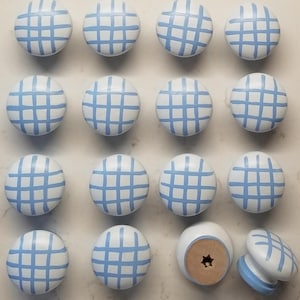 May include: A set of 16 blue and white checkered cabinet knobs. The knobs are made of wood and have a smooth, rounded surface. They are perfect for adding a touch of farmhouse style to any room.