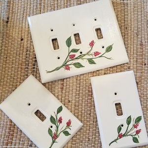 May include: Three white ceramic light switch covers with a hand-painted design of a green leafy branch with red berries.