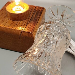 Puede incluir: Una peque&ntilde;a base de l&aacute;mpara de madera con una pantalla de vidrio transparente. La pantalla tiene un dise&ntilde;o decorativo de vidrio cortado. Una bombilla est&aacute; encendida dentro de la pantalla.