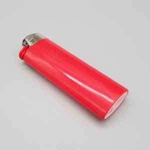May include: A red plastic lighter with a silver top and a white plastic base.