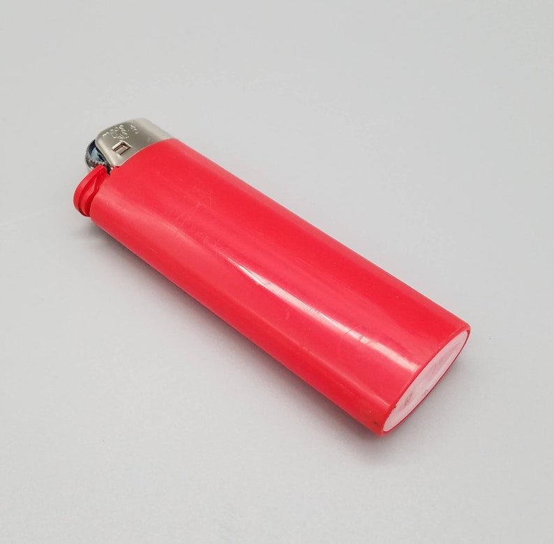 May include: A red plastic lighter with a silver top and a white plastic base.