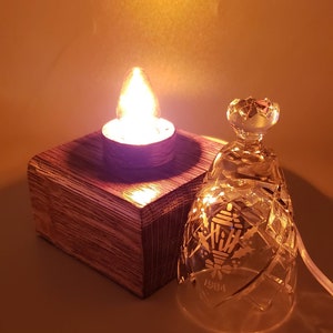 May include: A wooden base with a lit candle and a clear glass bell with a holly and lantern design and the year 1984 etched on the side.